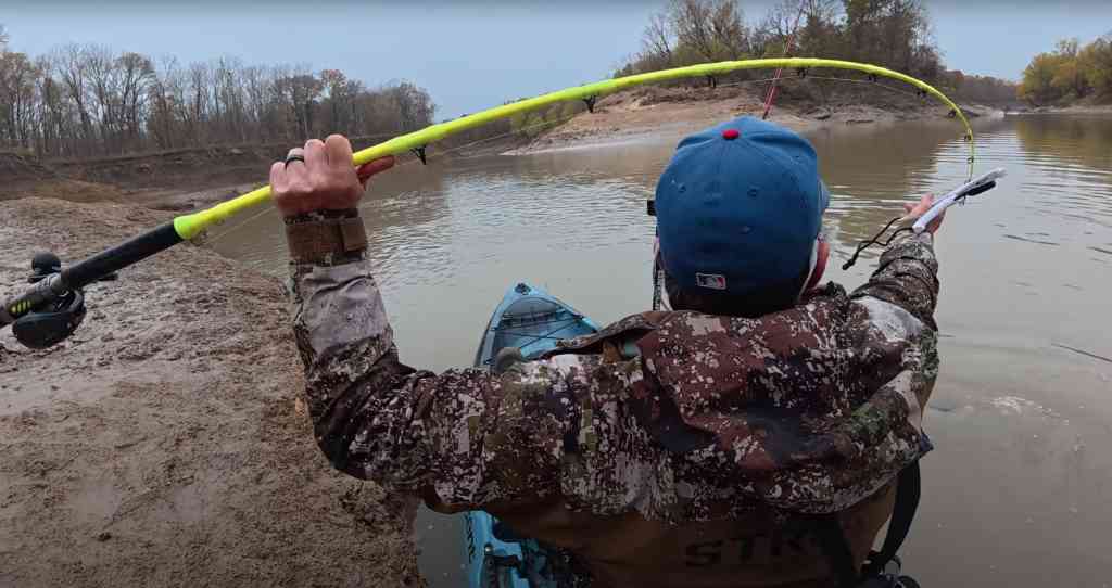 Spencer Bauer’s bright-green Hellcat rod bends sharply as he reels in a feisty winter catfish from his kayak.